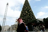 Un Palestinien le 20 décembre 2016 près d'un sapin de Noël géant place de la Mangeoire, à côté de l'Eglise de la Nativité, à Béthléem, lieu de naissance du Christ selon la Bible