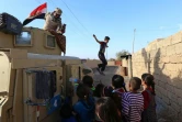 Des enfants jouent près d'un blindé des forces irakiennes patrouillant dans une rue du village de Jarif, à environ 45 kilomètres au sud de Mossoul, le 12 novembre 2016