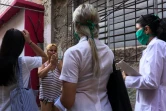 Liz Caballero Gonzalez (g), médecin, et deux étudiantes en médecine font du porte à porte dans le quartier du Vedado, le 31 mars 2020 à La Havane, pendant l'épidémie de coronavirus à Cuba