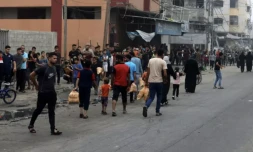 Des habitants portent des sacs de pain tandis que d'autres font la queue devant une boulangerie, le 28 octobre 2023 à Gaza ( AFP / MOHAMMED ABED )