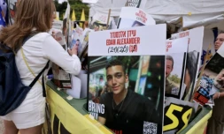 Une femme regarde des portraits d’otages israéliens détenus dans la bande de Gaza, dont un au centre représentant l’otage israélo-américain Edan Alexander, dont la libération est attendue le 12 mai 2025, sur la place des otages à Tel-Aviv, le 12 mai 2025 ( AFP / Menahem KAHANA )