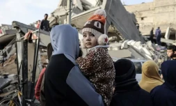 Un Palestinien porte un enfant devant les décombres d'une maison détruite par un bombardement israélien à Rafah, dans le sud de la bande de Gaza, le 3 février 2024 ( AFP / SAID KHATIB )