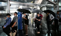 Des personnes attendent un taxi à la station de métro de Chiba, dans la ville de Chiba à l'est de Tokyo, le 13 août 2026, alors que de fortes pluies s'abattent sur la région