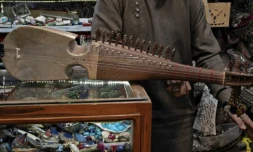 Gull Agha, un joueur amateur afghan de rubab, présente l'instrument dans un magasin à Herat, le 21 décembre 2024 ( AFP / Wakil KOHSAR )