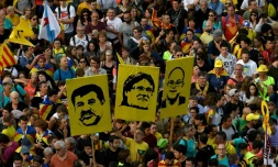 Des personnes tiennent des portraits des séparatistes catalans Jordi Sanchez, Carles Puigdemont et Jordi Turull lors d'une manifestation à Barcelone, le 18 octobre 2019