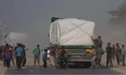Des Palestiniens se précipitent vers des camions transportant de l'aide humanitaire alors qu'ils traversent Deir al-Balah, dans le centre de Gaza, le dimanche 9 novembre 2025.