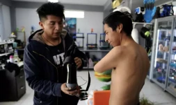 Roly Mamani (g) explique le fonctionnement de la prothÚse de bras bionique qu'il a conçue pour Marco Antonio Nina, le 8 janvier 2024 à Achocalla, en Bolivie ( AFP / JORGE BERNAL )