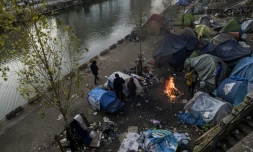 Des migrants se rĂ©chauffent autour d'un feu, le 23 fĂ©vrier 2018 Ă  Paris oĂč un froid sibĂ©rien est attendu