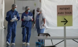 Des membres du personnel médical en combinaison de protection organisent l'accueil des patients au "centre d'urgences Covid-19" aménagé dans un gymnase, le 23 mars 2020 à Taverny, dans le Val d'Oise
