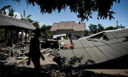 Un homme marche près d'un bâtiment effondré dans le village de Sugian sur l'île indonésienne de Lombok secouée par une série de séismes, le 20 août 2018