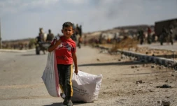 Un garçon palestinien porte un sac et traîne un autre derrière lui alors qu'il revient d'un point de distribution alimentaire dans le centre de la bande de Gaza, le 5 octobre 2025 ( AFP / Eyad BABA )