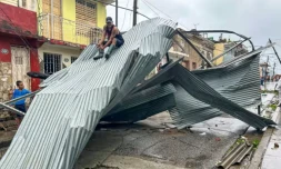Un homme assis sur une partie du toit de sa maison, Ă Santiago de Cuba, le 29 octobre 2025 ( AFP / YAMIL LAGE )