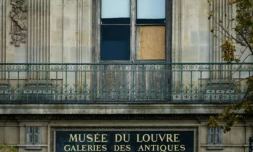 Une fenêtre du musée du Louvre protégée par un panneau de bois après un vol de bijoux, le 20 octobre 2025 à Paris ( AFP / Dimitar DILKOFF )