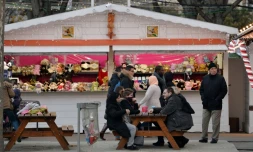 Des personnes s'asseoient devant un stand de jouets, au marché de Noël à Paris, le 24 décembre 2015