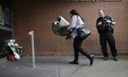 Une femme dépose des fleurs devant le commissariat de Roubaix en hommage aux trois policiers morts la veille dans un accident de la route, le 22 mai 2023 dans le Nord ( AFP / Sameer Al-Doumy )