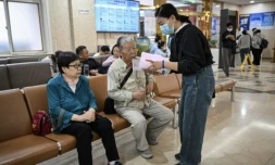 Meng Jia (d), une accompagnatrice de patient, prend en charge Gao Yingmin (g) et Tian Yigui (c) pour les guider dans un hôpital à Pékin, le 22 mai 2025 ( AFP / Jade GAO )
