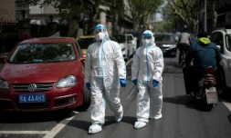 Des habitants en combinaison intégrale de protection dans une rue de Wuhan, le 7 avril 2020 dans la province chinoise du Hubei