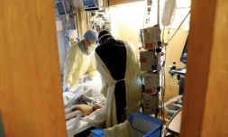 Une infirmière militaire se penche sur un patient atteint du Covid-19 ( AFP / JEFF KOWALSKY )