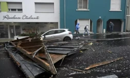 Des piétons passent près du toit arraché d'un immeuble résidentiel tombé dans une rue de Brest, après le passage de la tempête Ciaran, le 2 novembre 2023 dans le Finistère ( AFP / DAMIEN MEYER )