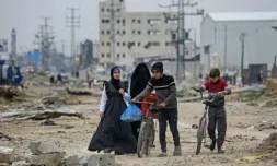 Des jeunes Palestiniens marchent autour des décombres dans le camp de réfugiés de Maghazi, dans le centre de la bande de Gaza, en partie détruit par les bombardemebnts israéliens, le 27 février 2024 ( AFP / - )