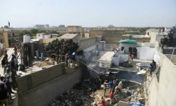 Des équipes de secours arrosent les débris d'un avion de la compagnie Pakistan International Airlines qui s'est écrasé sur un quartier résidentiel de Karachi, le 22 mai 2020 au Pakistan