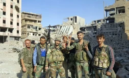 Des forces du régime syrien font le V de la victoire au milieu des destructions dans la ville de Deir Ezzor d'où les jihadistes ont été chassés, le 3 novembre 2017