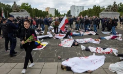 Des manifestants allongés sur le sol, simulent des corps de victimes, pour protester contre l'invasion russe de l'Ukraine, au mausolée des soldats soviétiques à Varsovie, en Pologne, le 9 mai 2025