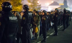 Des policiers slovènes encadrent les migrants sur le point de monter dans un bus le 28 octobre 2015 à Sentilj 