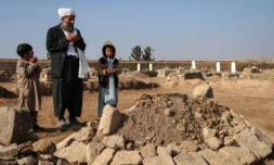 Gul Ahmad, au centre, et des proches prient sur la tombe de Habibullah dans le village de Ghunjan, en Afghanistan, le 26 décembre 2025 ( AFP / Mohsen KARIMI )