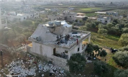 Des habitants dans les décombres d'une maison partiellement détruite après une opération des  forces spéciales américaines aboutissant à la mort du chef de l'EI Abou Ibrahim al-Hachimi al-Qourachi, le 3 février 2022 à Atmé, en Syrie