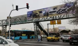 Scène de rue à Téhéran, où une bannière montrant une voiture brûlée proclame "Ceci n'est pas une protestation", le 15 janvier 2026 ( AFP / ATTA KENARE )