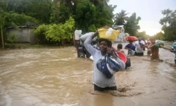 Des résidents traversent la Route Nationale 2 inondée à L'Acul, à l'ouest de Port-au-Prince, le 3 juin 2023 ( AFP / Richard PIERRIN )