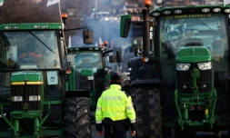 Un policier se tient devant des tracteurs bloquant l'autoroute A6, le 31 janvier 2024 près de Chilly-Mazarin en Essonne