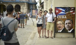 Des touristes posent devant une photo de Obama et Castro, le 19 mars 2016, à l'entrée d'un restaurant à la Havane, la veille de l'arrivée historique du président américain à Cuba