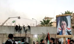 Des soutien du leader religieux chiite Moqtada Sadr, dont l'effigie s'affiche sur un panneau (d), essaient d'escalader la barrière devant l'ambassade de Suède à Bagdad, le 20 juillet 2023 ( AFP / Ahmad AL-RUBAYE )