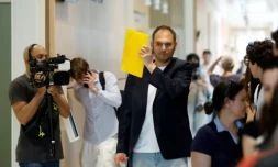 David G., animateur pĂ©riscolaire, se cache le visage avec un dossier Ă son arrivĂ©e au tribunal oĂč il doit ĂȘtre jugĂ© pour agressions sexuelles sur neuf enfants, le 26 mai 2026 ( AFP / SIMON WOHLFAHRT )