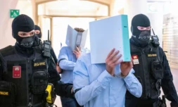 Des prévenus cachent leurs visages derrière un dossier, escortés par des policiers vers la salle d'audience du tribunal de Wiener Neustadt, le 28 mai 2026 en Atriche, lors du procès pour un complot contre un concert de la star américaine Taylor Swift à Vienne ( AFP / Joe Klamar )