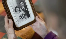 Jeanne Tournellec regarde la photo de mariage de sa sĆur Catherine Tournellec, violĂ©e par un soldat amĂ©ricain, et de son beau-frĂšre Jean Salaun, chez elle Ă Locmaria-Plouzane, le 14 mars 2024 dans le FinistĂšre ( AFP / Fred TANNEAU )
