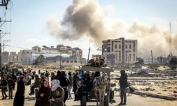 Des Palestiniens fuient Khan Younès dans le sud de la bande de Gaza, avec en arrière-plan un nuage de fumée s'élevant après des bombardements, le 30 janvier 2024 ( AFP / Mahmud Hams )