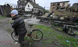 Un homme passe à côté d'un blindé russe et d'un bâtiment détruits à Gostomel, près de Kiev, le 22 avril 2022