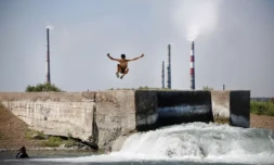 Un adolescent plonge dans de l'eau rejetée par le complexe métallurgique de Kazakhmys à Balkhach au Kazakhstan, le 20 juin 2024 ( AFP / Ruslan PRYANIKOV )