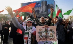 Des Iraniens brandissent des drapeaux et des pancartes lors d'un rassemblement de protestation contre l'attaque américaine en Iran sur la place Enghelab à Téhéran, le 22 juin 2025 ( AFP / ATTA KENARE )