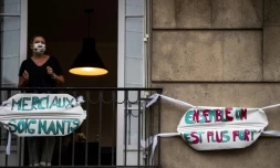 Une femme applaudit les soignants depuis le balcon de son appartement à Saint-Mandé, en banlieue parisienne, le 4 mai 2020 à 20h