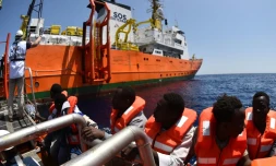 Des migrants montent à bord de l'Aquarius, aprÚs avoir été secourus le 24 mai 2016 en mer Méditerranée par SOS Méditerranée