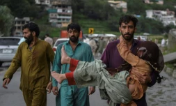 Un homme porte sa fille malade le long d'une route endommagée par les eaux de crue suite aux fortes pluies de mousson dans la région de Madian, dans la vallée de Swat, au nord du Pakistan, le 27 août 2022