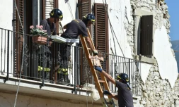 Des pompiers aident les habitants à récupérer leurs affaires personnelles dans les maisons endommagées par le séisme, le 28 août 2016 à Amatrice, dans le centre de l'Italie