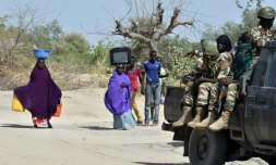 Des soldats nigériens passent devant des personnes qui fuient les islamistes de Boko Haram, le 25 mai 2015 à Malam Fatori