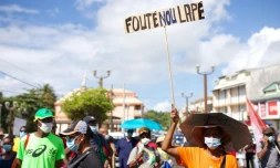 Militants de l'Union générale des travailleurs de Guadeloupe, faisant rouler des pneus pour installer un barrage à Perrin Les Abymes, en Guadeloupe, le 17 novembre 2021