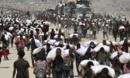 Des Palestiniens transportent des sacs de farine près de Jabalia, le 27 juillet 2025, après que des camions transportant de l'aide humanitaire sont entrés dans le nord de la bande de Gaza.  AFP - AFP or licensors - BASHAR TALEB