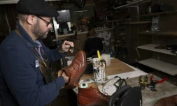 Le maître artisan cordonnier Thierry Hoo cire des chaussures qu'il a réparées dans la cordonnerie familiale "A la ville à la montagne", le 8 novembre 2023 à Paris